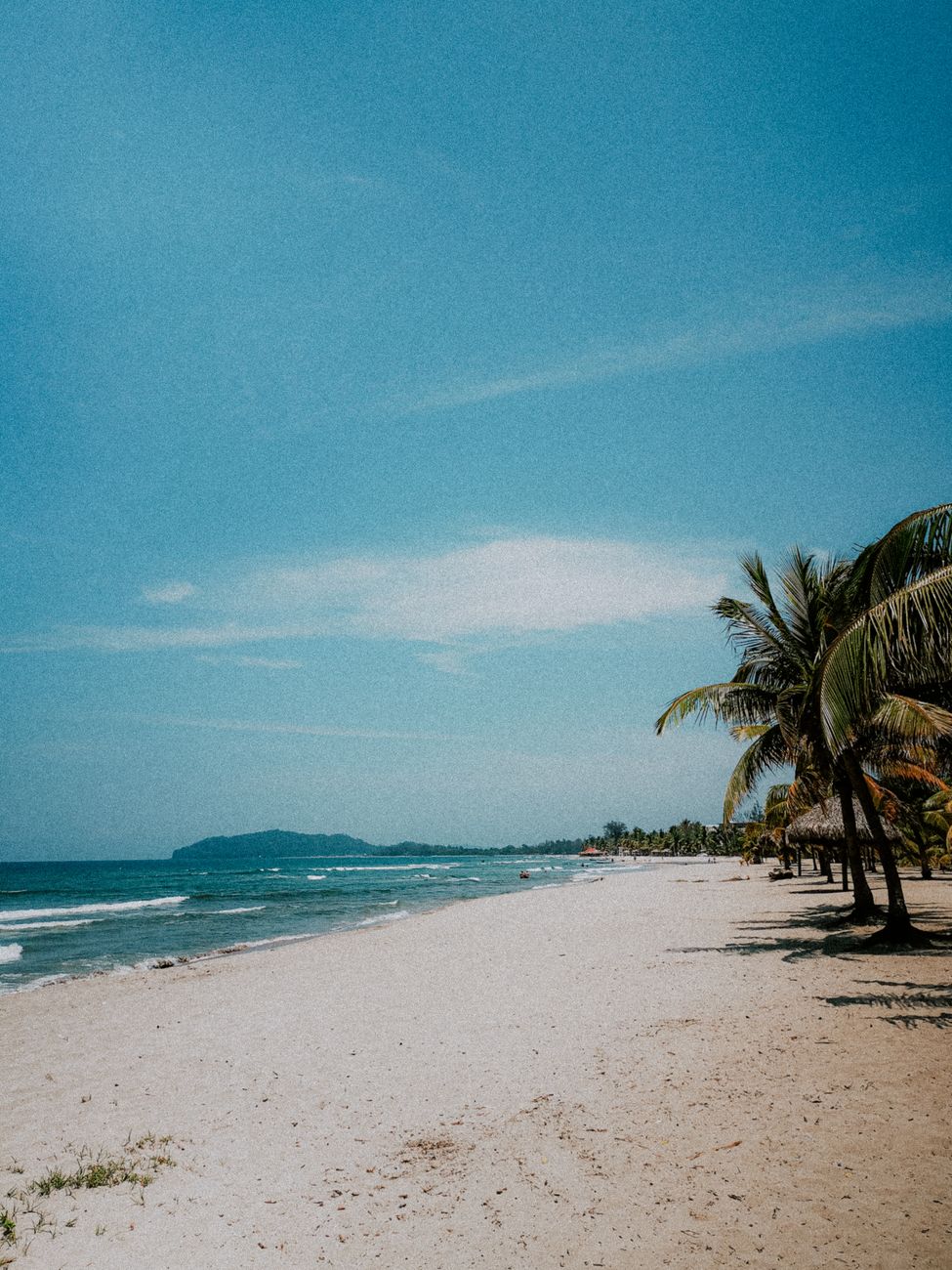 Pantai pasir putih dengan air laut jernih dan pokok kelapa di Langkawi